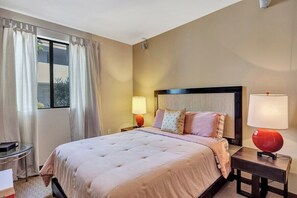Quarto de hotel com cama, duas mesas de cabeceira, janela com cortinas e vista externa.