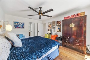 A bedroom with a bed, a ceiling fan, a wardrobe, and various wall decorations. - Charming single-story condo boasts three bedrooms (Palm Springs)