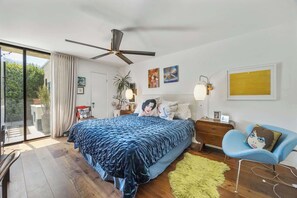 Een slaapkamer met een groot bed, een plafondventilator, een bureau en een stoel.