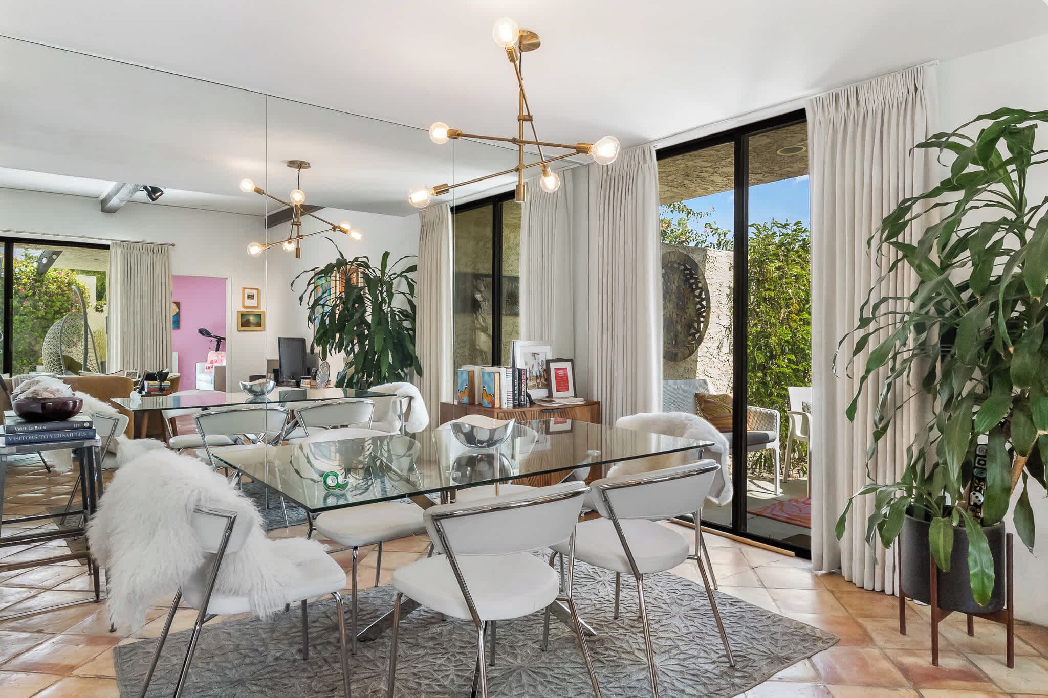 Un espace repas moderne avec une table en verre, des chaises blanches et un lustre.