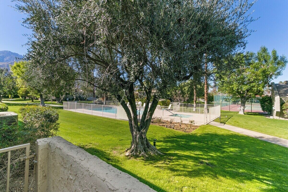Un patio con arboles, una piscina y una cancha de tenis.