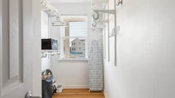 A narrow hallway with a wooden floor, a window with blinds, a radiator, and a white wall with a hook.