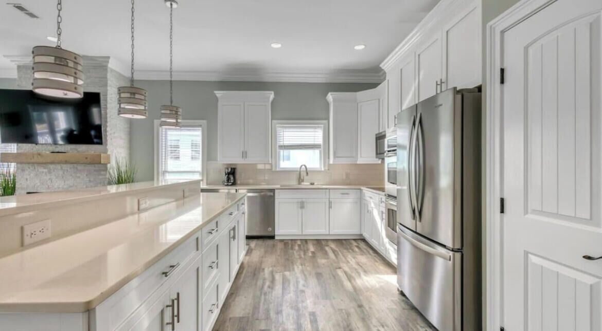 Una cocina moderna con armarios blancos, electrodomésticos de acero inoxidable y piso de madera.