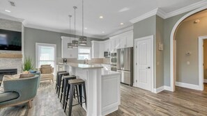 A modern kitchen with white cabinetry, stainless steel appliances, and a central island with bar stools. - Walk to Beach: 9BR Miramar Retreat - Pool and Grill (Destin)
