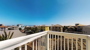A residential area with a clear view of the ocean, featuring houses with various roof styles and a white balcony railing. - Walk to Beach: 9BR Miramar Retreat - Pool and Grill (Destin)