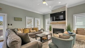 A living room with a fireplace, a television mounted above it, and a sofa set. - Walk to Beach: 9BR Miramar Retreat - Pool and Grill (Destin)