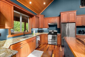 A kitchen with wooden cabinets, stainless steel appliances, and a granite countertop. - Private Mountain Estate | Riverfront | Mt. Rainier (Packwood)