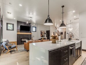 A modern kitchen with a marble island, pendant lighting, and a built-in oven. - Chic Crown Heights Retreat W/ Fire Pit, Near Paseo (Oklahoma City)