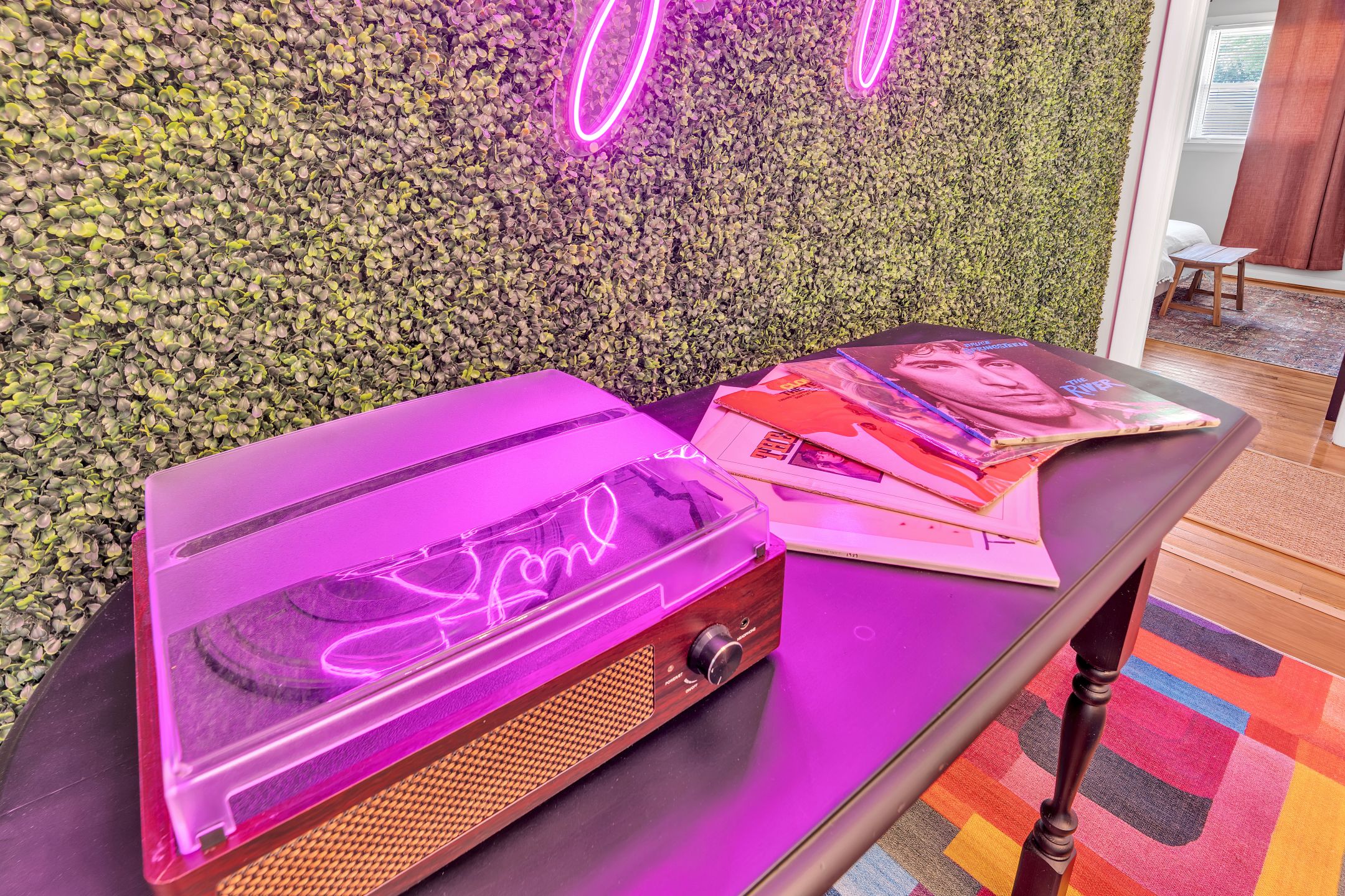 Une table avec une lampe néon, une radio et des magazines.