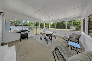 A covered patio with a grill, a table, and chairs. - The Peach Haus ~ Groovy Stay With Screened Porch (Tifton)