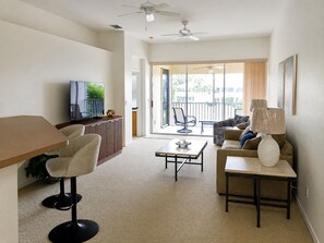 En moderne stue med et fladskærms TV, en sofa, et sofabord og en loftsvifte.