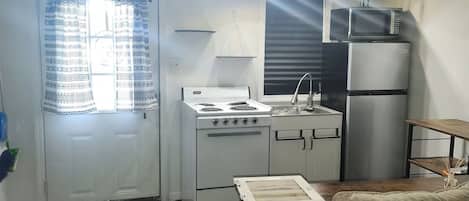 A compact kitchen with a stove, sink, and refrigerator.