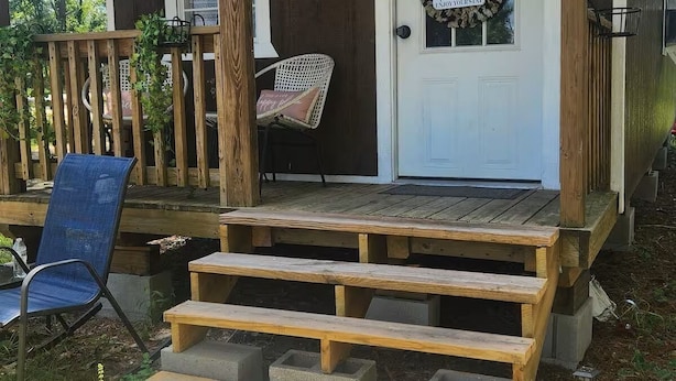 A wooden cabin with a porch, a welcome sign, and a bench. - The Dasher Den is a Cozy Tiny Cabin located right off of Highway 41 (Valdosta)