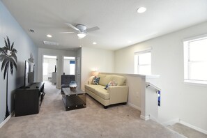 A spacious living room with a beige sofa, a coffee table, and a ceiling fan. - Princess/StarWars 5-bedroom house in Orlando near Parks (Kissimmee)