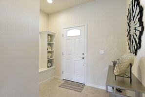 A hallway with a white door, a shelf with decorative items, and a wall-mounted abstract art piece. - Princess/StarWars 5-bedroom house in Orlando near Parks (Kissimmee)
