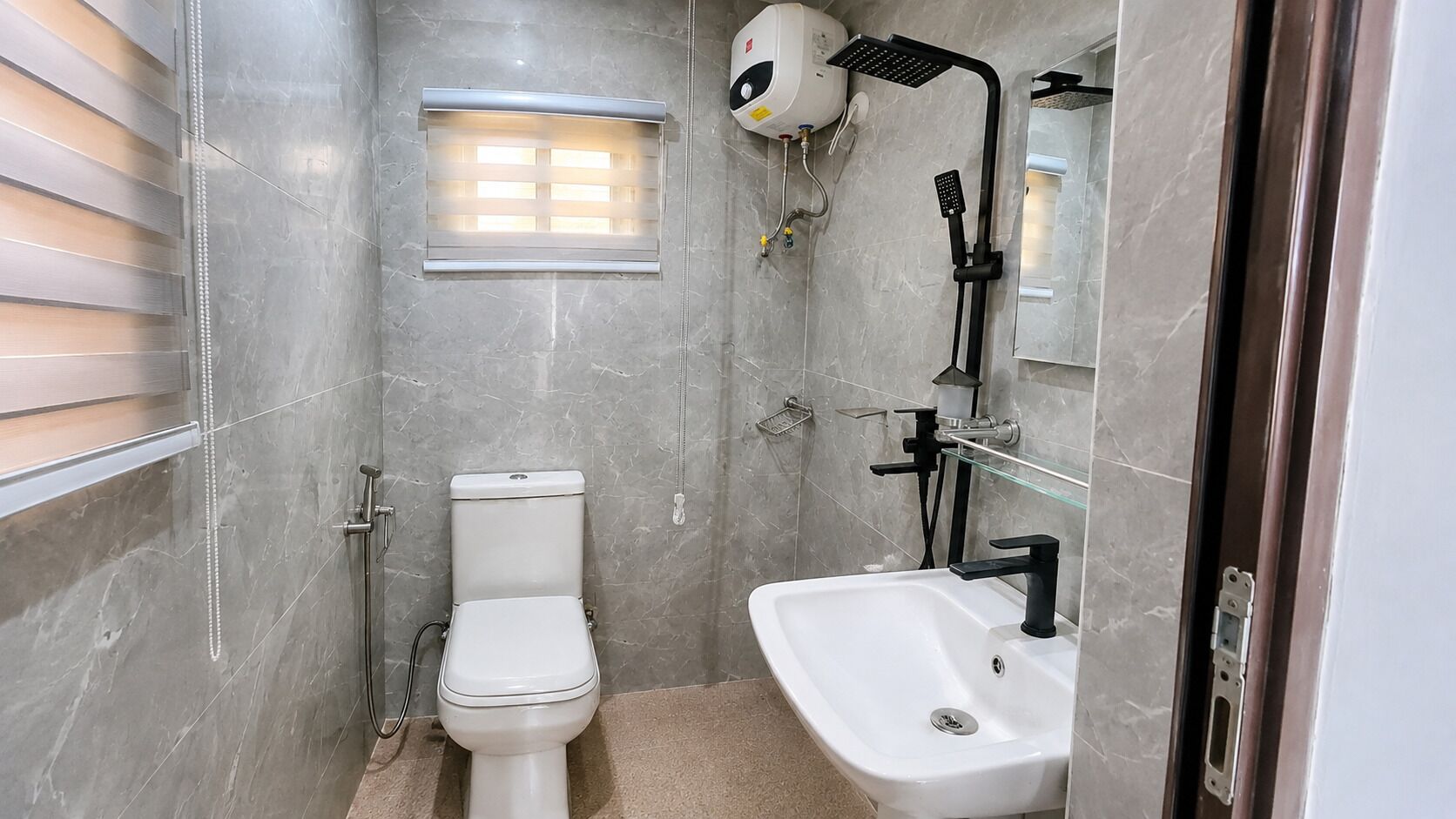 A compact bathroom with a toilet, a glass shower enclosure, and a sink.