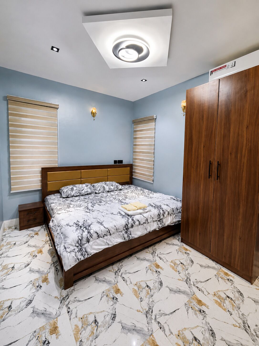A bedroom with a bed, a wardrobe, and a ceiling light fixture.