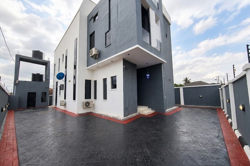 Un edificio moderno de dos pisos con techo plano, ventanas amplias y una combinación de colores rojo y gris.