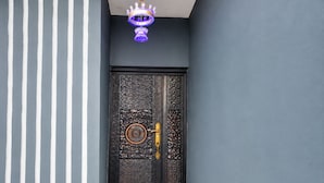 Una porta blu scuro con decorazioni elaborate e una maniglia dorata, che dà accesso a una scala in marmo.