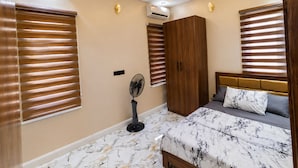 Una camera da letto con un letto, un armadio, una ventola portatile e un lampadario.