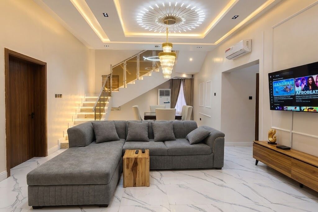 Un soggiorno moderno con un divano componibile, un tavolino in legno, una TV e una scala.