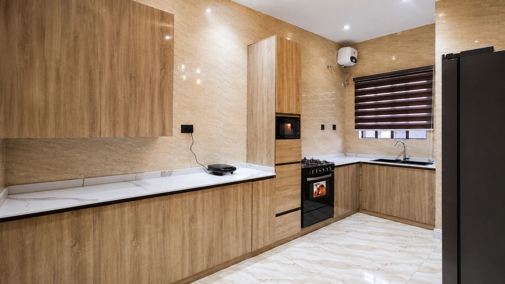 Una cocina moderna con armarios de madera, estufa negra y encimera de mármol.