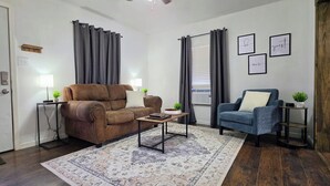 A living room with a brown sofa, a blue armchair, a coffee table, and a patterned rug.