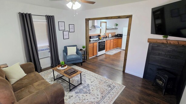 A living room with a sofa, a coffee table, a fireplace, and a kitchen in the background.