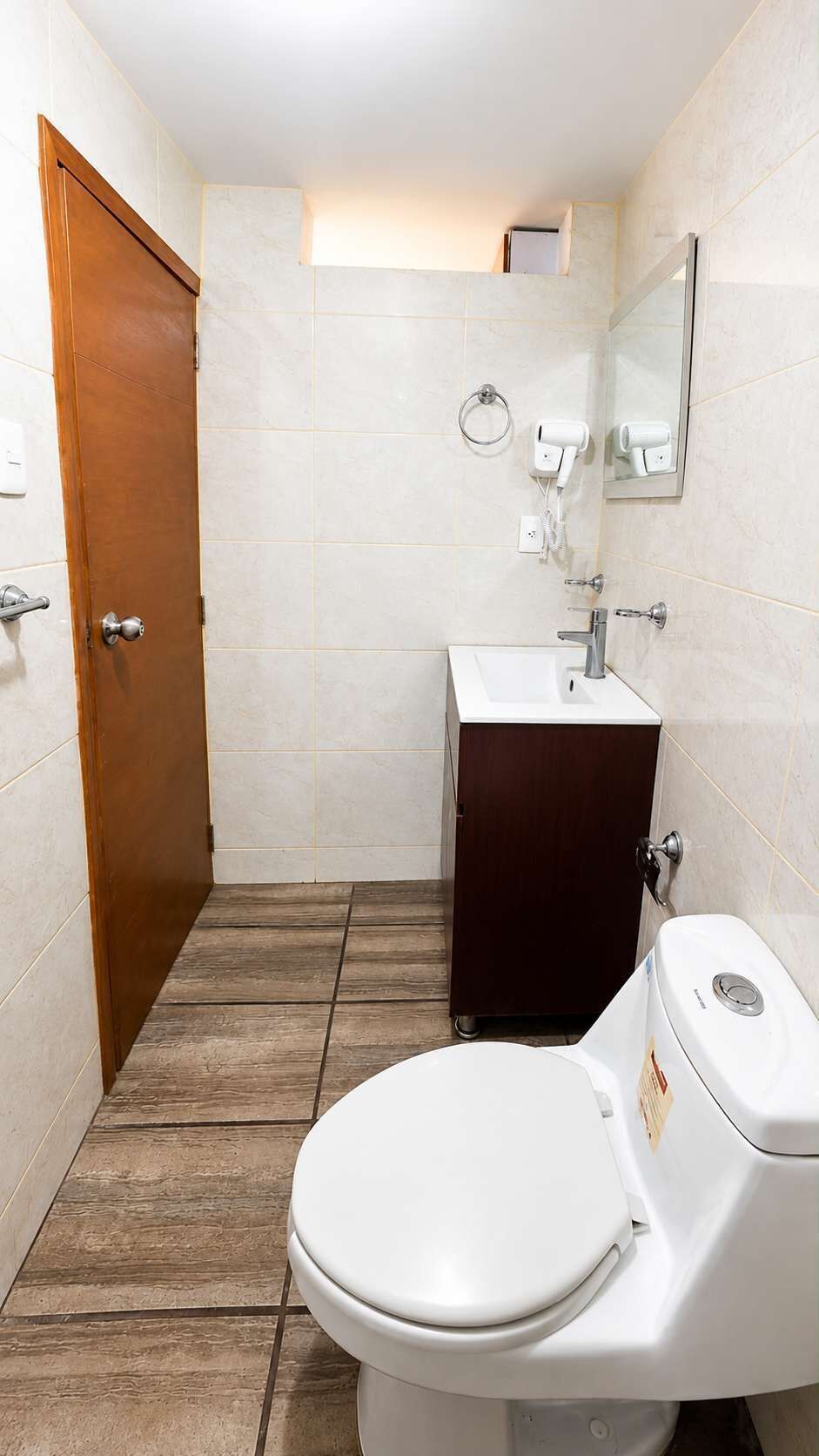 Une salle de bain avec des toilettes, un lavabo et une porte en bois.