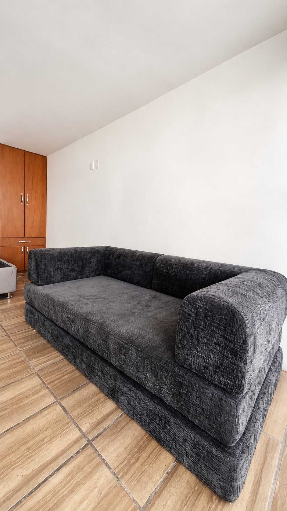 Un canapé gris dans une pièce dotée d’un plancher en bois et d’une armoire en bois.