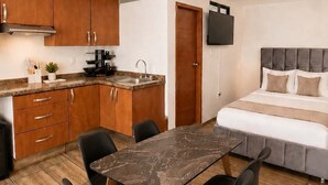 A compact room with a kitchenette, a dining area with a marble table, and a bed with a grey headboard. - BOWRA SUITE PRIVADA 1, COLONIA AMERICANA (Guadalajara)