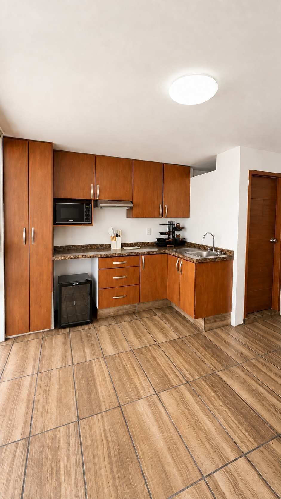 Une cuisine moderne avec des meubles en bois, un four à micro-ondes encastré et un évier en acier inoxydable.