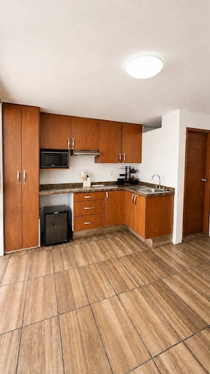 Eine moderne Küche mit Holzschränken, einer integrierten Mikrowelle und einer Spüle aus Edelstahl.