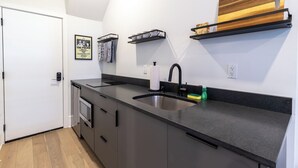 Una cucina moderna con un piano di lavoro nero, lavello in acciaio inossidabile ed scaffali in legno.