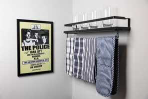 Une affiche encadrée du groupe « The Police », avec Joan Jett et les Blackhearts, une serviette à carreaux et un porte-verres contenant des verres.