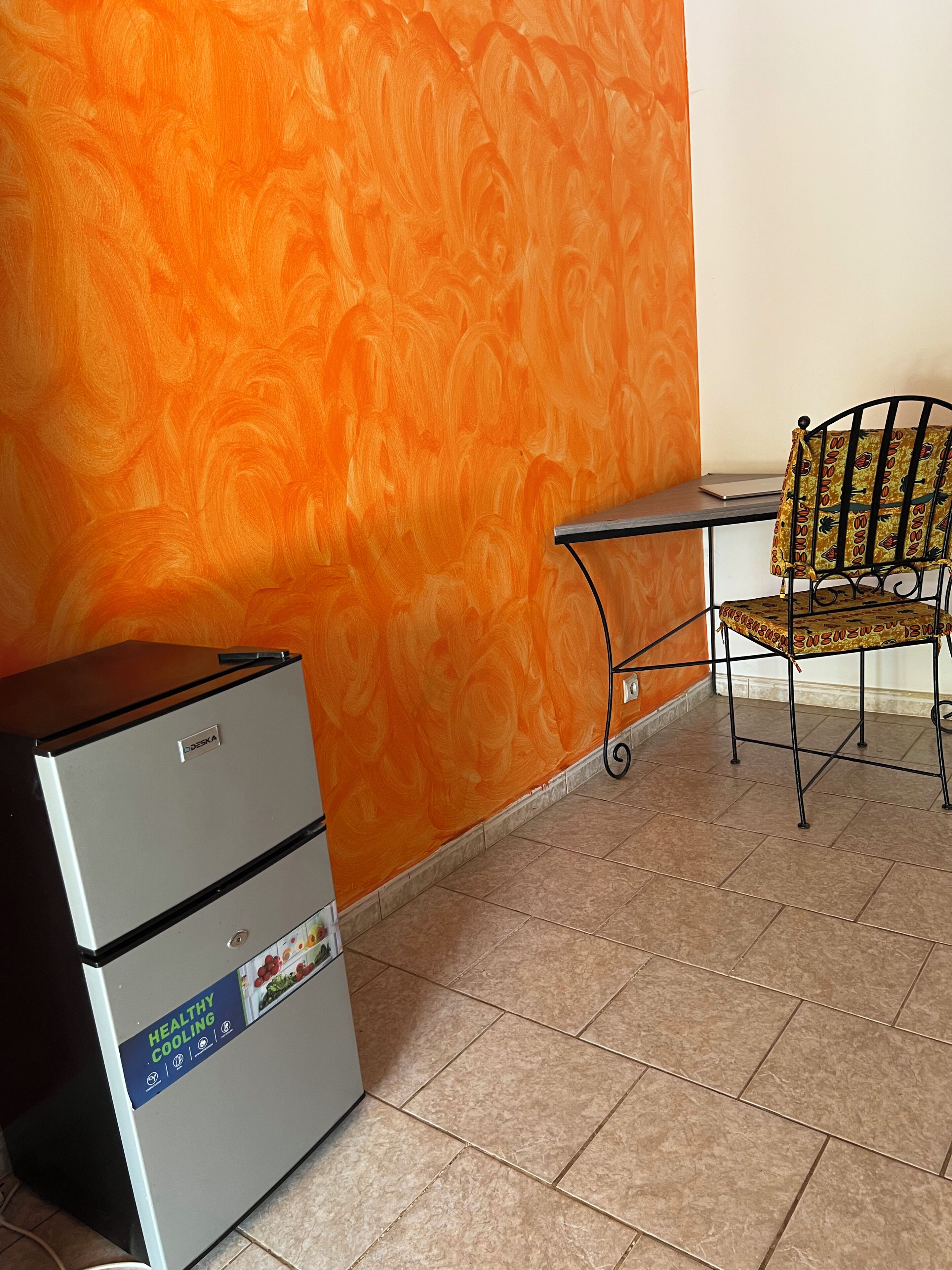 A room with a refrigerator, a chair, and a tiled floor.