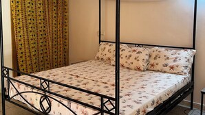 Una cama con dosel y cuatro columnas, un edredón estampado y almohadas a juego.