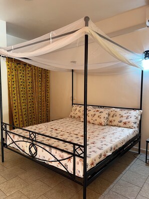 Una cama con dosel y cuatro columnas, un edredón estampado y almohadas a juego.