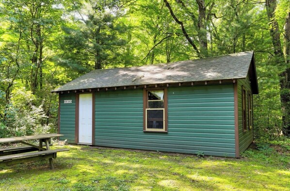 A small, single-story cabin with a door and a window, surrounded by trees. - Cozy 1-bedroom cabin in charming Grand Junction with AC (Grand Junction)