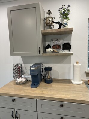 Eine Küchenarbeitsplatte mit einer Keurig-Kaffeemaschine, einem Kaffee-Pod-Halter, einem Mixer, einem Wasserkocher und einer Rolle Küchenpapier.
