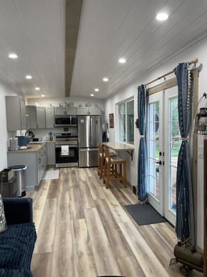 A modern kitchen with stainless steel appliances, wooden chairs, and a dining table. - Railroad Retreat in Moose Pass – Car 0037 (Moose Pass)