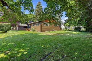 A single-story house with a well-maintained lawn and a large tree in the foreground.
