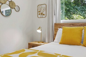 A bedroom with a bed, a bedside table with a lamp, a mirror, and a wall decoration.