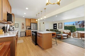 A modern kitchen with wooden cabinets, a stainless steel refrigerator, and a central island.