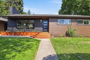 A modern two-story house with a front porch, a garage, and a well-maintained lawn.