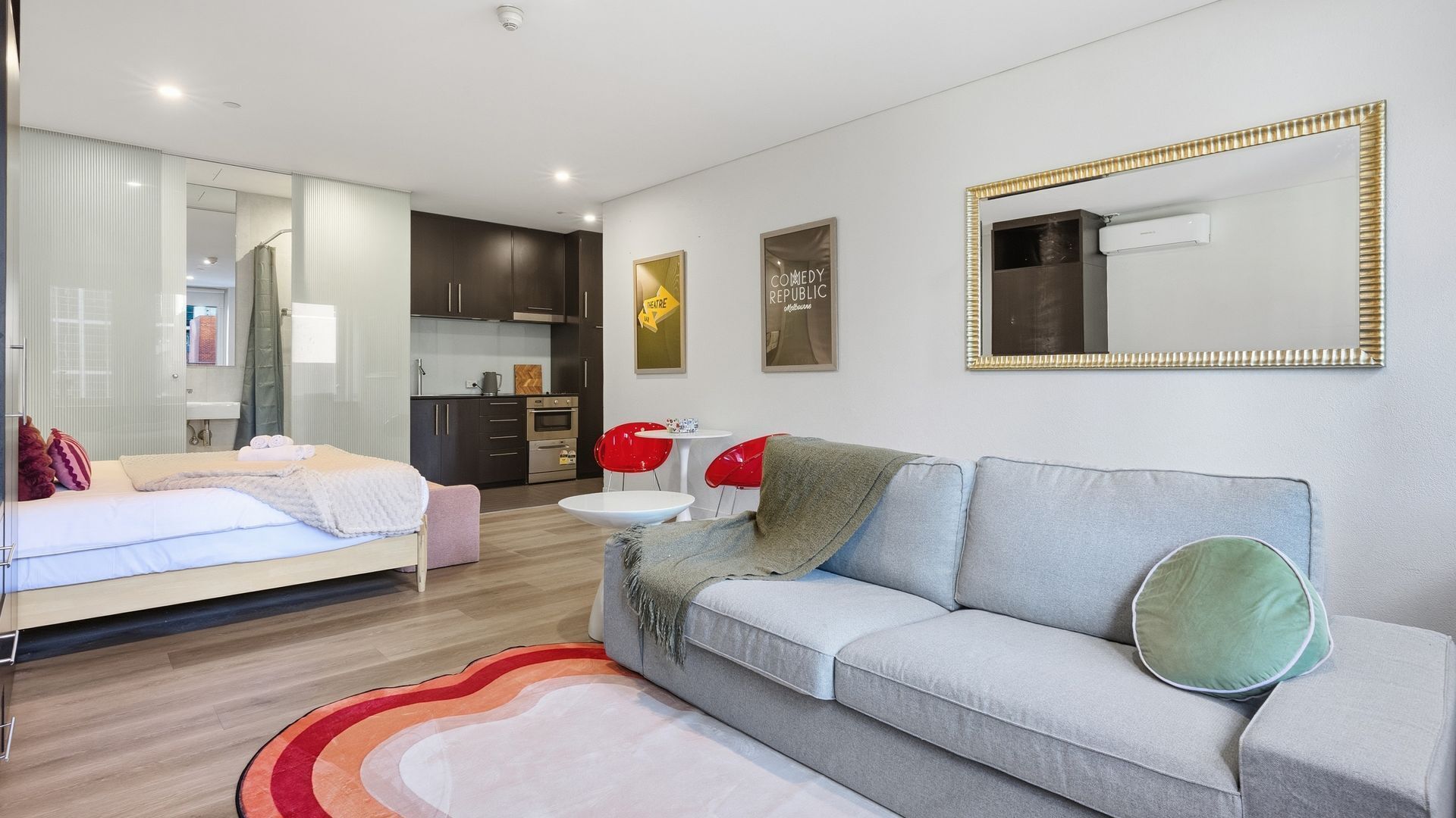 Una habitación de hotel moderna con cama, sofá, comedor y cocina.