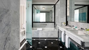 Un baño moderno con bañera, dos lavamanos y un espejo grande.