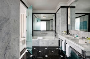 Een moderne badkamer met een badkuip, twee wasbakken en een grote spiegel.