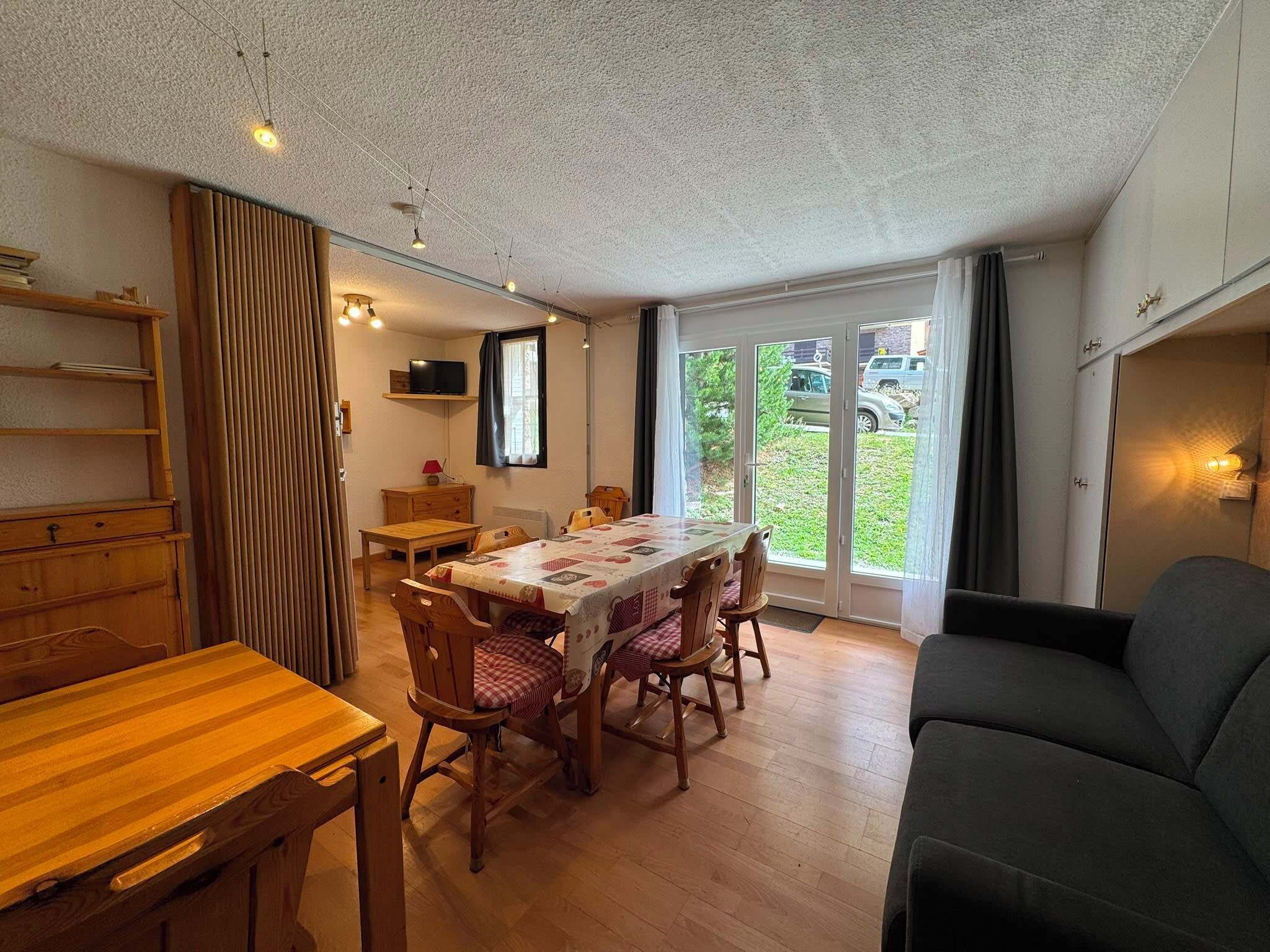 A dining area with a wooden table, chairs, and a television on a shelf.