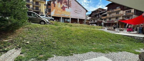 A building with a large outdoor advertisement, a grassy area, and a parking lot with cars.